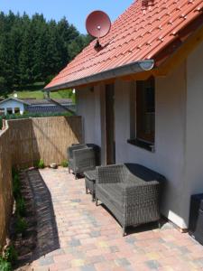 a patio with three wicker chairs under a roof at Apartments Monika Schneider in Wimbach