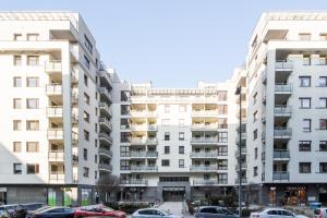 un immeuble d'appartements avec des voitures garées dans un parking dans l'établissement Warsaw Night Apartments Giełdowa, à Varsovie