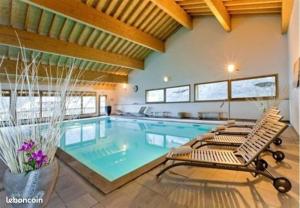 a large swimming pool with two lounge chairs next to it at Appartement chaleureux au ski avec piscine in Orelle