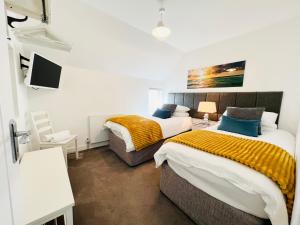 a bedroom with two beds and a desk and a tv at Lundy SeaView Great Sea-views in Westward Ho