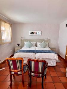 a bedroom with a large bed and two chairs at Baywatch Paternoster -The Villa in Paternoster