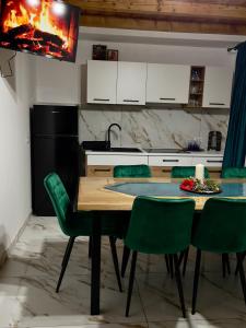 a kitchen with a wooden table and green chairs at Cabana Lavinia Daniel in Statjunea Borsa