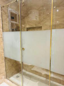 una ducha con puerta de cristal en una habitación en شارع شومان من الاستاد en Tanta