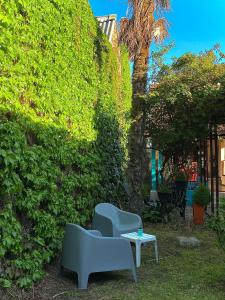 een paar stoelen en een tafel naast een heg bij Hostel Che Viajero in Villa Gesell
