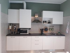 eine Küche mit weißen Schränken und einer Mikrowelle in der Unterkunft Casa Coralba in Pavia