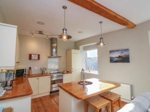 uma cozinha com armários brancos e um balcão de madeira em 1 Bailey's Cottage em Dartmouth