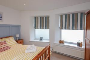 a bedroom with a bed and two windows with towels at 1 Bailey's Cottage in Dartmouth