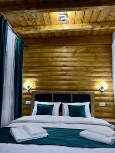 a bedroom with a large bed with a wooden wall at Cabana Lavinia Daniel in Statjunea Borsa