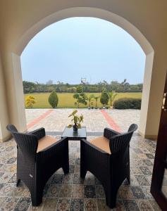 a patio with two chairs and a table with a view at Bundeli Kothi - a unique farmstay in Orchha