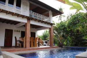 a villa with a swimming pool and a house at Villa Kayu Padangbai in Padangbai