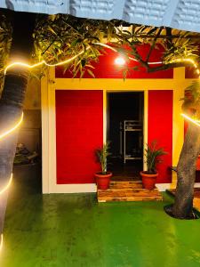 a house with red walls and potted plants and lights at Hostel kuruku santhu colive in Pondicherry