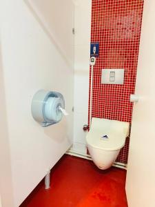 La salle de bains est pourvue de toilettes et d'un mur en carrelage rouge. dans l'établissement TRANSIT, à Istanbul