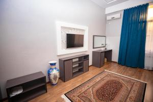 a living room with a television and a vase on the floor at VATAN DUSHANBE HOTEL in Dushanbe