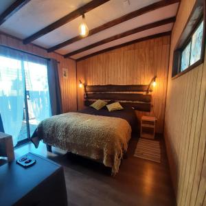 ein Schlafzimmer mit einem Bett in einem Zimmer mit Holzwänden in der Unterkunft Refugio Zen Spa in Putaendo