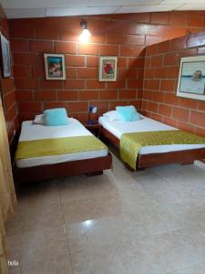 two beds in a room with a brick wall at Cabañas La Honda in Guatapé