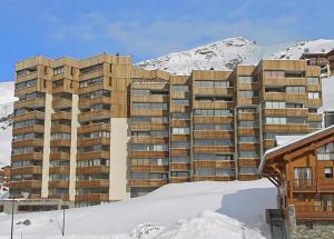 a building in the snow next to a mountain at SUPERBE 2 P et CABINE , Plein sud, 8 COUCHAGES STYLE CHALET in Val Thorens