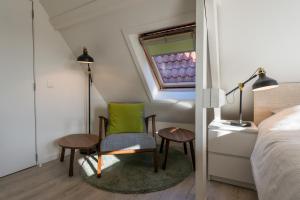 een slaapkamer met een stoel, een tafel en een raam bij Well Thirteen by Romy&Travis in Brugge