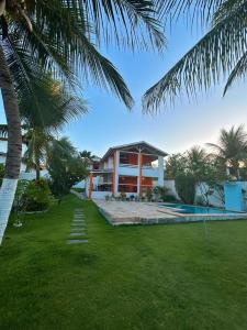 a house with a swimming pool and a palm tree at Pousada Aryanne in Pecém