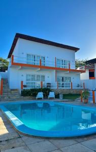 a villa with a swimming pool in front of a house at Pousada Aryanne in Pecém
