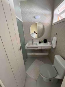 uma casa de banho com um WC, um lavatório e um espelho. em Casa Girassol em Pipa