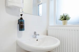 a white bathroom with a sink and a soap dispenser at Stratford Great Rooms to stay - 20 in London