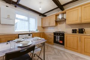 una cocina con armarios de madera y una mesa con platos. en Stratford Great Rooms to stay - 20, en Londres