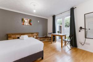 1 dormitorio con cama, escritorio y ventana en Stratford Great Rooms to stay - 20, en Londres