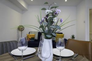 a table with two glasses and a vase with flowers at Adelles seaside retreat in Hove