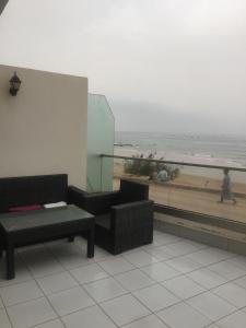 a balcony with a table and a couch and the beach at Holikeys - Agadir - 2 Ch - Aourir 005 in Agadir