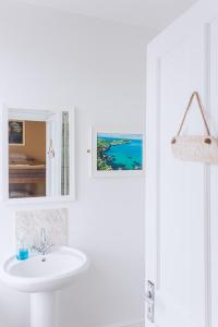 Baño blanco con lavabo y espejo en Smarties Surf Lodge en Newquay