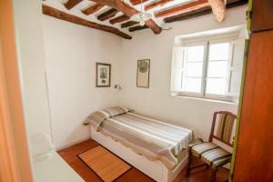 een slaapkamer met een bed, een raam en een stoel bij L'Orto dei Bruchi in Collodi