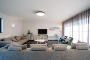 un soggiorno con divano, sedie e TV di Vakantiewoning Amico a Gistel