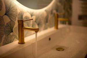 a sink with a gold faucet in a bathroom at Loft/Jacuzzi L'instant in Saint-Valery-en-Caux