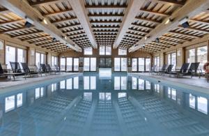 a large swimming pool with chairs in a building at Appartement T3 ARC 1950 skis aux pieds Sauna, Hammam, Jacuzzi in Arc 1950