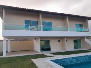 a house with a balcony and a swimming pool at Meu Chale Flecheiras in Flecheiras