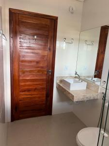 a bathroom with a wooden door and a sink at Meu Chale Flecheiras in Flecheiras
