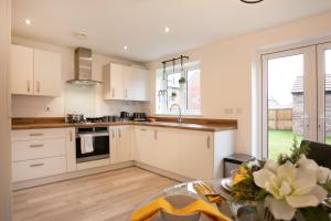 a kitchen with white cabinets and a table at Jasmine House in Nottingham