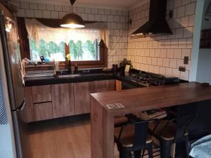 a kitchen with a sink and a counter with chairs at Hermosa cabaña con hot tub. in Talagante