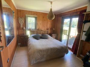 1 dormitorio con 1 cama en una habitación con paredes de madera en Hermosa cabaña con hot tub. en Talagante