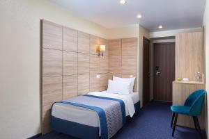 een hotelkamer met een bed en een blauwe stoel bij VATAN DUSHANBE HOTEL in Doesjanbe