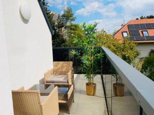 einen Balkon mit Korbstühlen und Pflanzen auf einem Gebäude in der Unterkunft Sunny Modern Apartment with Balcony - Free Parking in Wien