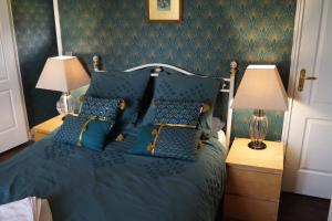 a bedroom with a blue bed with blue pillows at Maison Des Glycines in Droux