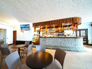 un restaurante con mesas y sillas y un bar en Hotel Arlecchino - Dada Hotels en Madesimo