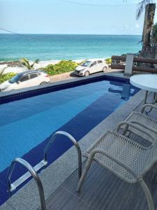 a swimming pool with a table and two cars on the beach at Vista incrível para o mar / Beautiful ocean view in Salvador