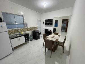 a kitchen and dining room with a table and a refrigerator at Casa nova e móveis novos in Caraguatatuba