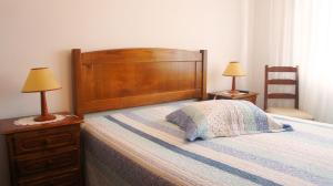 a bedroom with a bed with a wooden headboard and two lamps at Casa da Igreja by Gerês Casas in Geres
