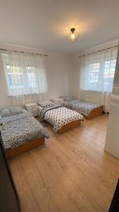 3 camas en una habitación con suelo y ventanas de madera en Dom #BESKIDZKA, en Rzeszów