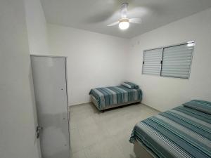 1 Schlafzimmer mit 2 Betten und einem Deckenventilator in der Unterkunft Casa nova e móveis novos in Caraguatatuba