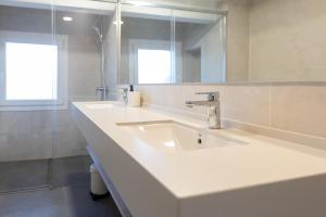 a white bathroom with two sinks and a mirror at Suitur beachfront apartment Roc de Sant Gaietà in Roda de Bará +19 photos