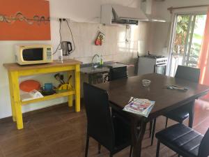 y cocina con mesa de comedor y microondas. en Casa en Atlántida, Barrio Español, Uruguay en Villa Argentina